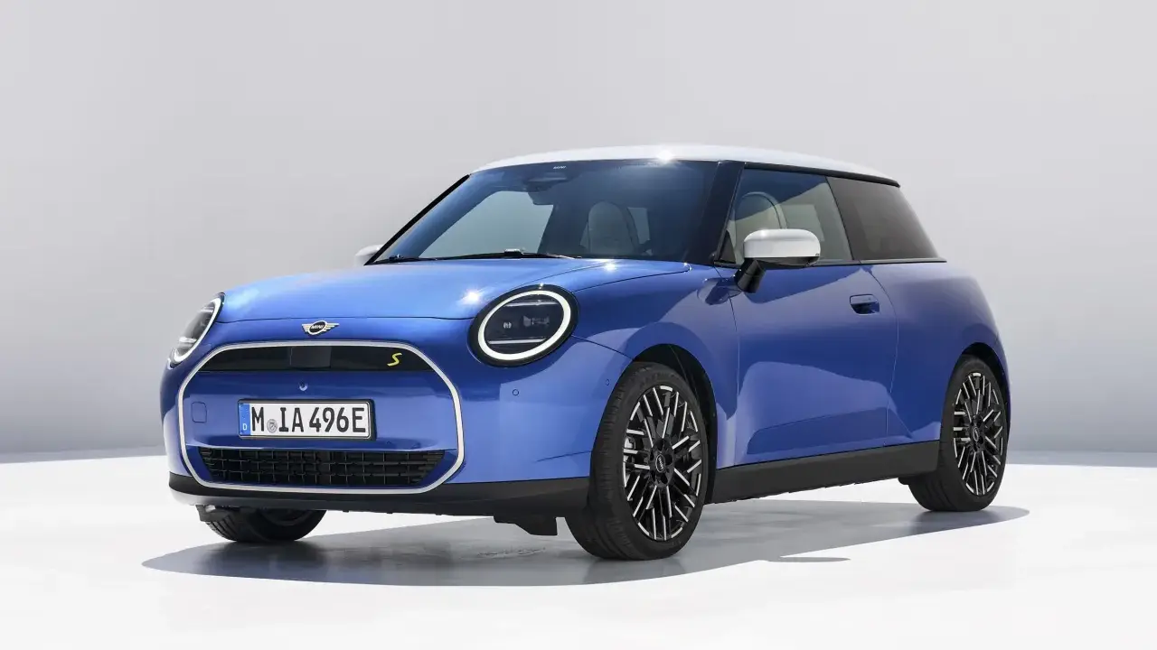 Niebieski Mini Cooper z białym dachem, jeden z tych małych aut, które pokochasz.