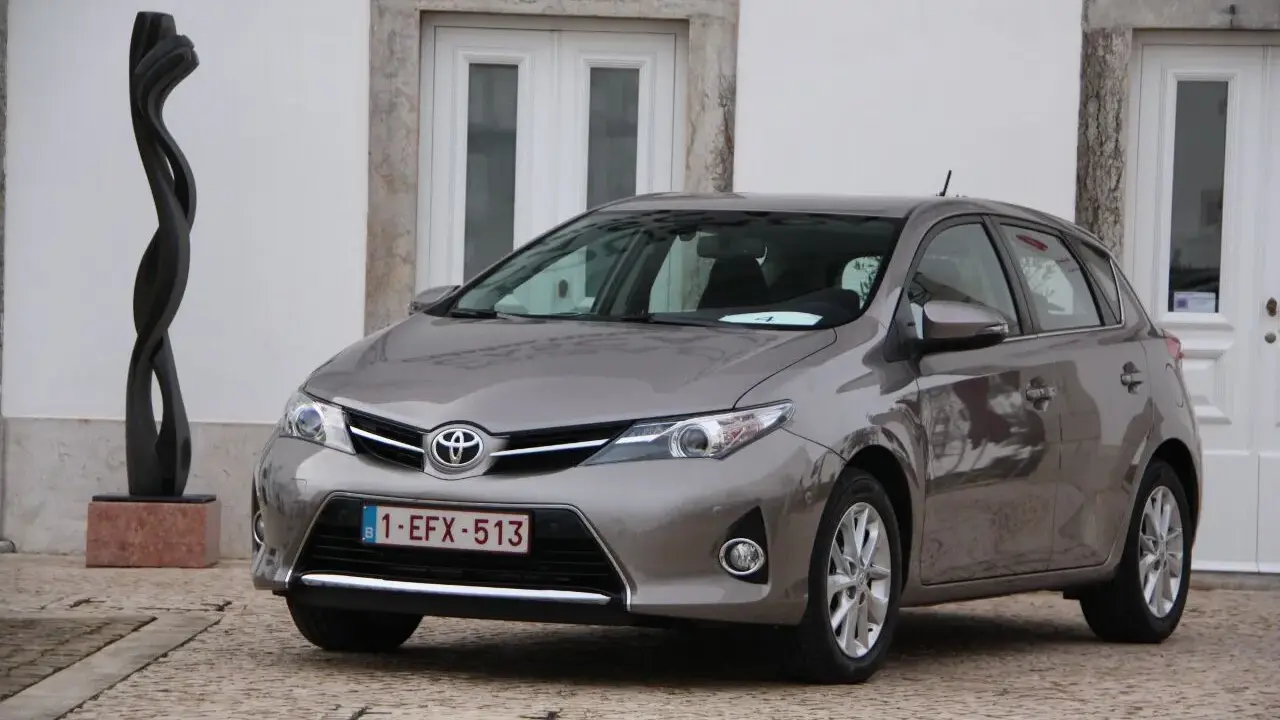 Szary Toyota Auris 1.6 benzyna, idealny do miasta, z niskim spalaniem. Obok rzeźba.