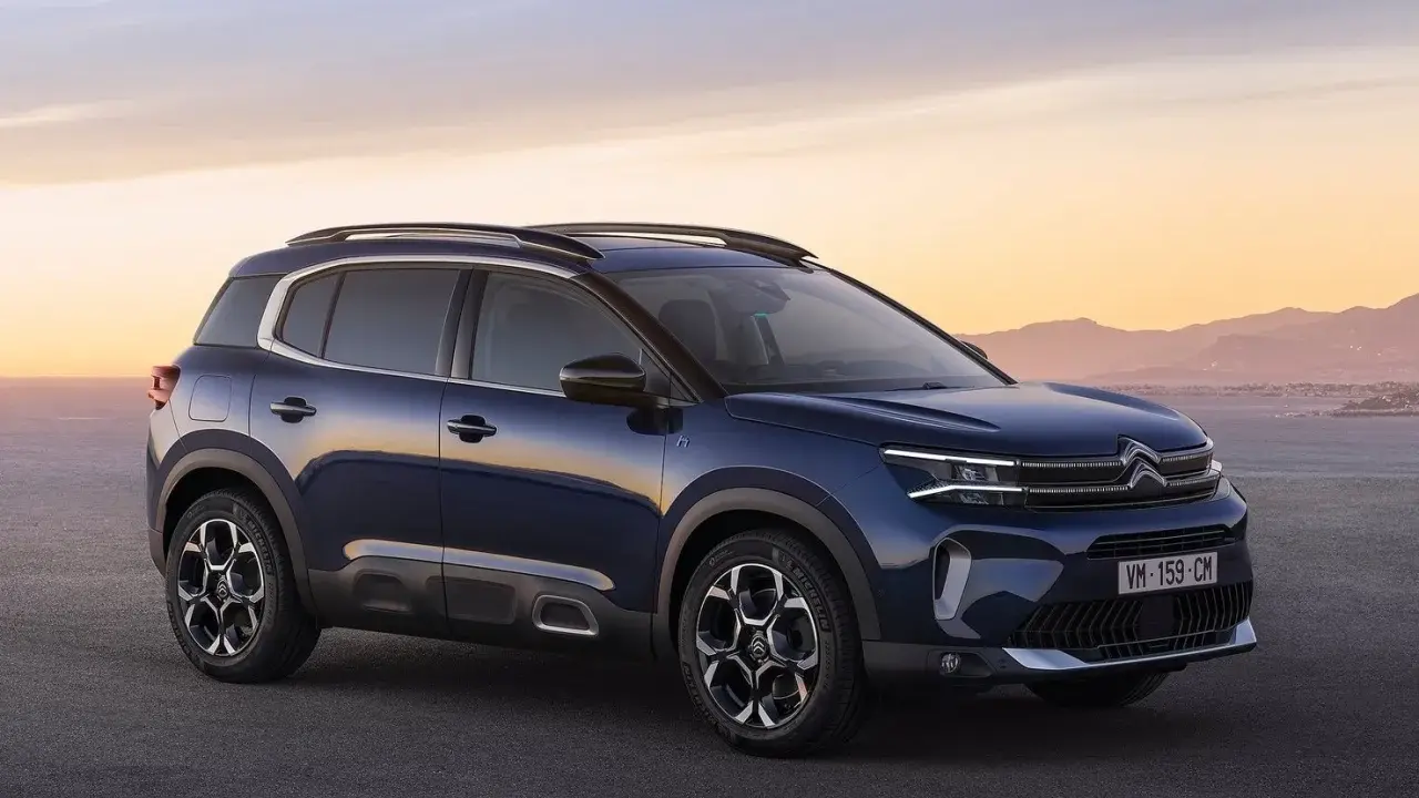 Ciemnoniebieski, kompaktowy SUV Citroën C5 Aircross na tle zachodzącego słońca nad morzem.