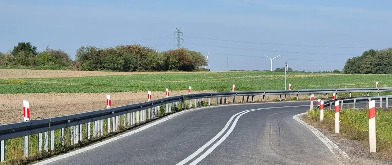 Oznaczenia na słupkach drogowych wzdłuż zakrętu drogi, prowadzącej przez pola i w pobliżu linii energetycznych.
