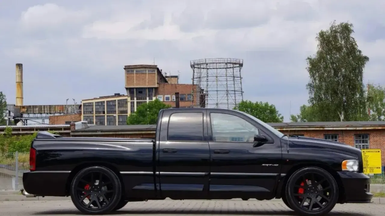 Czarny Dodge Ram 1500 SRT-10, potężny pickup, prezentuje swoje imponujące ramiona na tle postindustrialnego krajobrazu.