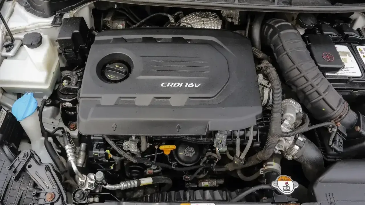 Silnik CRDi 1.6V w samochodzie. Widoczny czarny plastikowy dekiel silnika z napisem CRDi 16V, elementy układu dolotowego i chłodzenia.