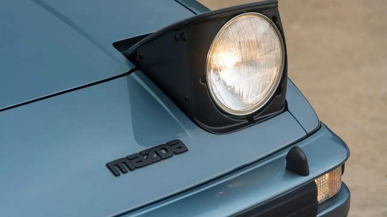 Mazda RX-7 z silnikiem Wankla. Charakterystyczny, wysuwany reflektor i logo marki na niebieskim lakierze.