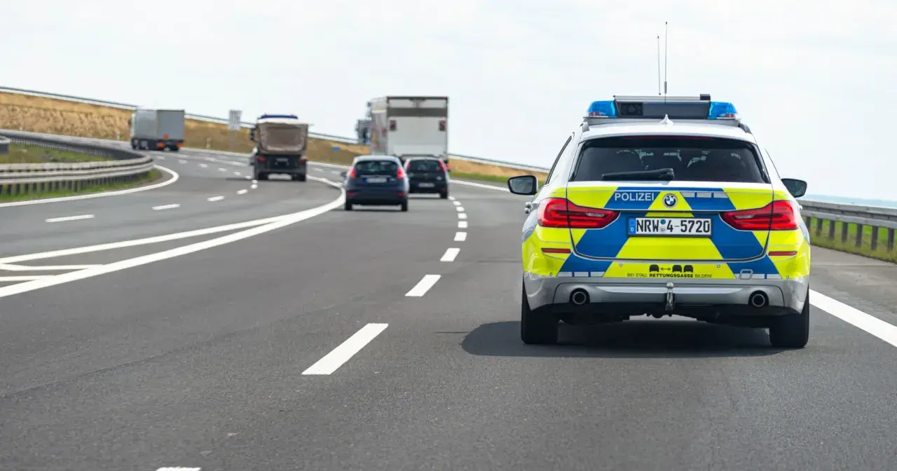 Niemiecka autostrada bez ograniczeń, gdzie policyjny radiowóz jedzie za innymi pojazdami.