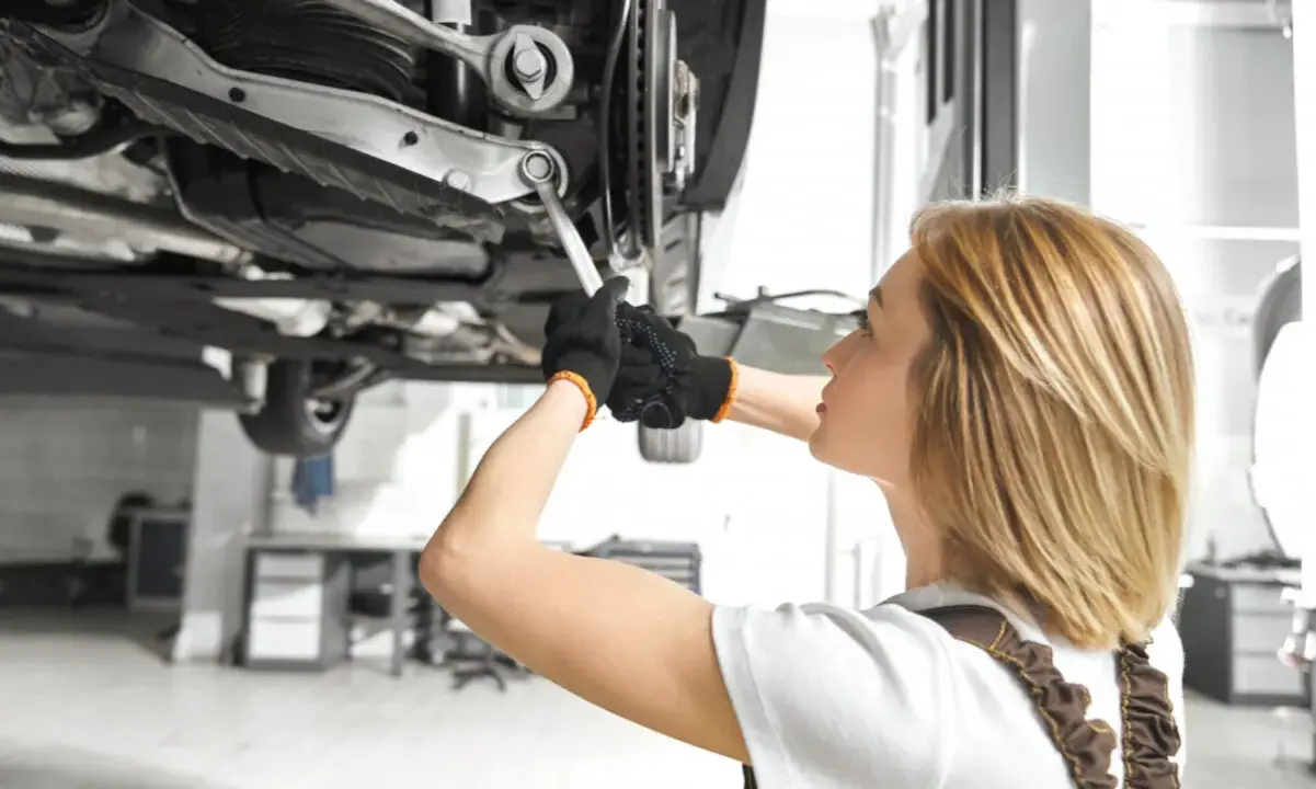 Mechanik sprawdza podwozie auta, szukając objawów uszkodzonego amortyzatora.