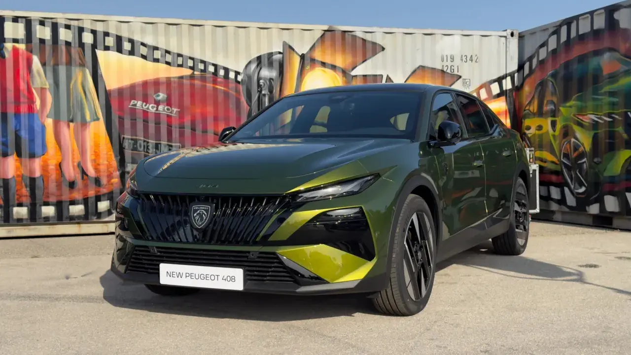 Nowy Peugeot 408 po lifcie, w kolorze zielonym, prezentuje się na tle kolorowych murali na kontenerach.