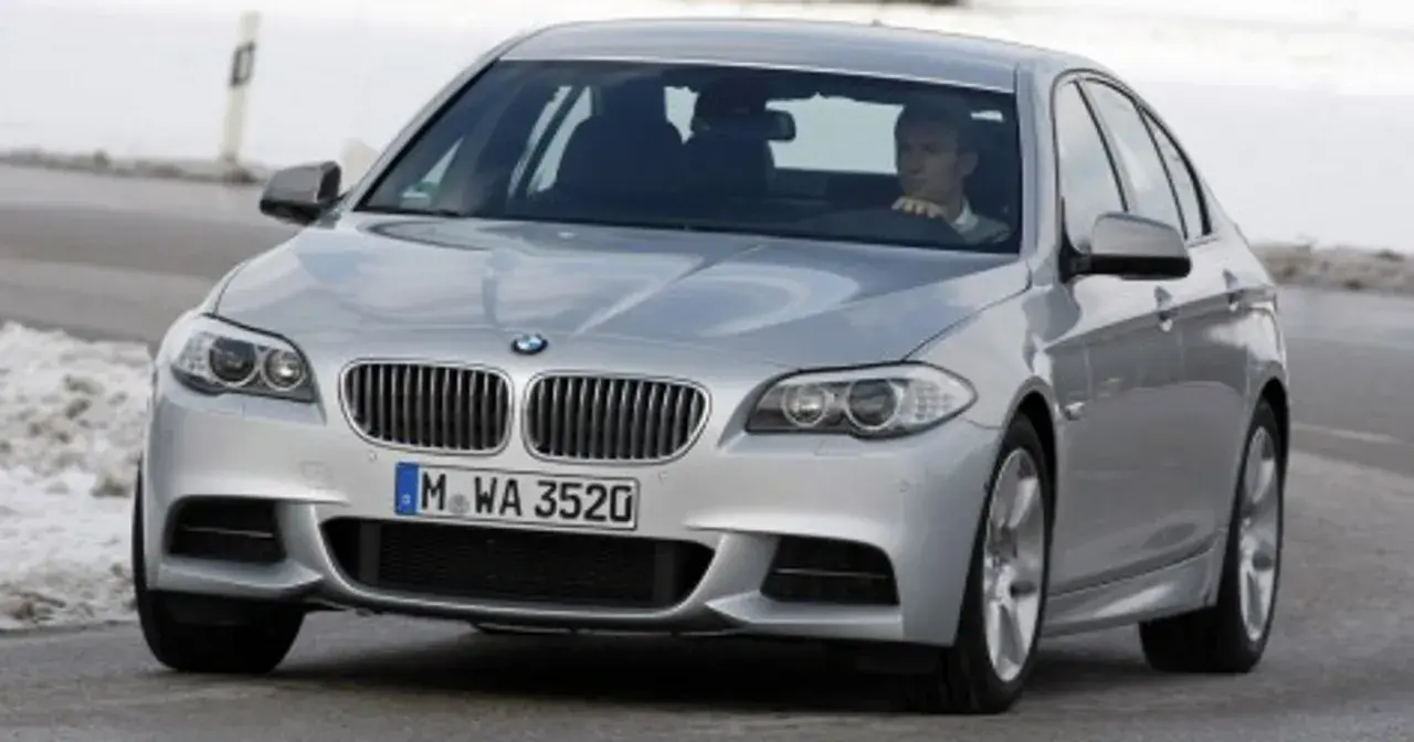 Srebrne BMW z kierowcą za kierownicą, gotowe do liftingu auta na zimowej drodze.