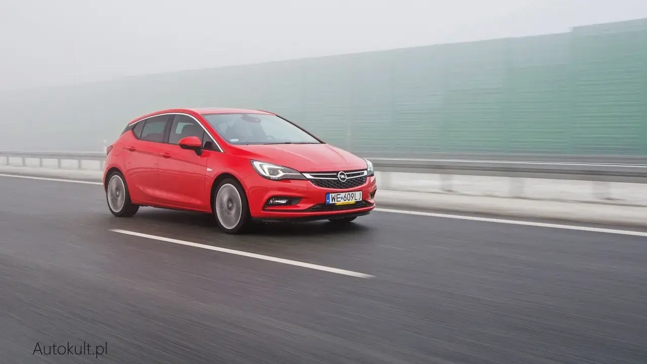 Czerwona Astra na autostradzie w mgle. Zastanawiasz się, ile pali Opel Astra? Ten model może być zaskakująco oszczędny.