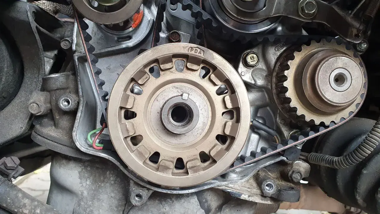 Zbliżenie na mechanizm silnika, widoczne koła zębate i pasek. Przygotowanie do wymiany rozrządu.
