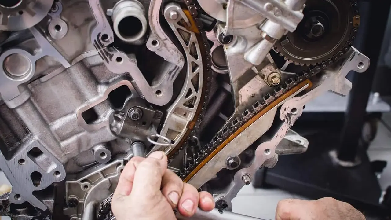 Mechanik naprawia rozrząd silnika. Luźny łańcuch może być jednym z objawów zużytej poduszki silnika.