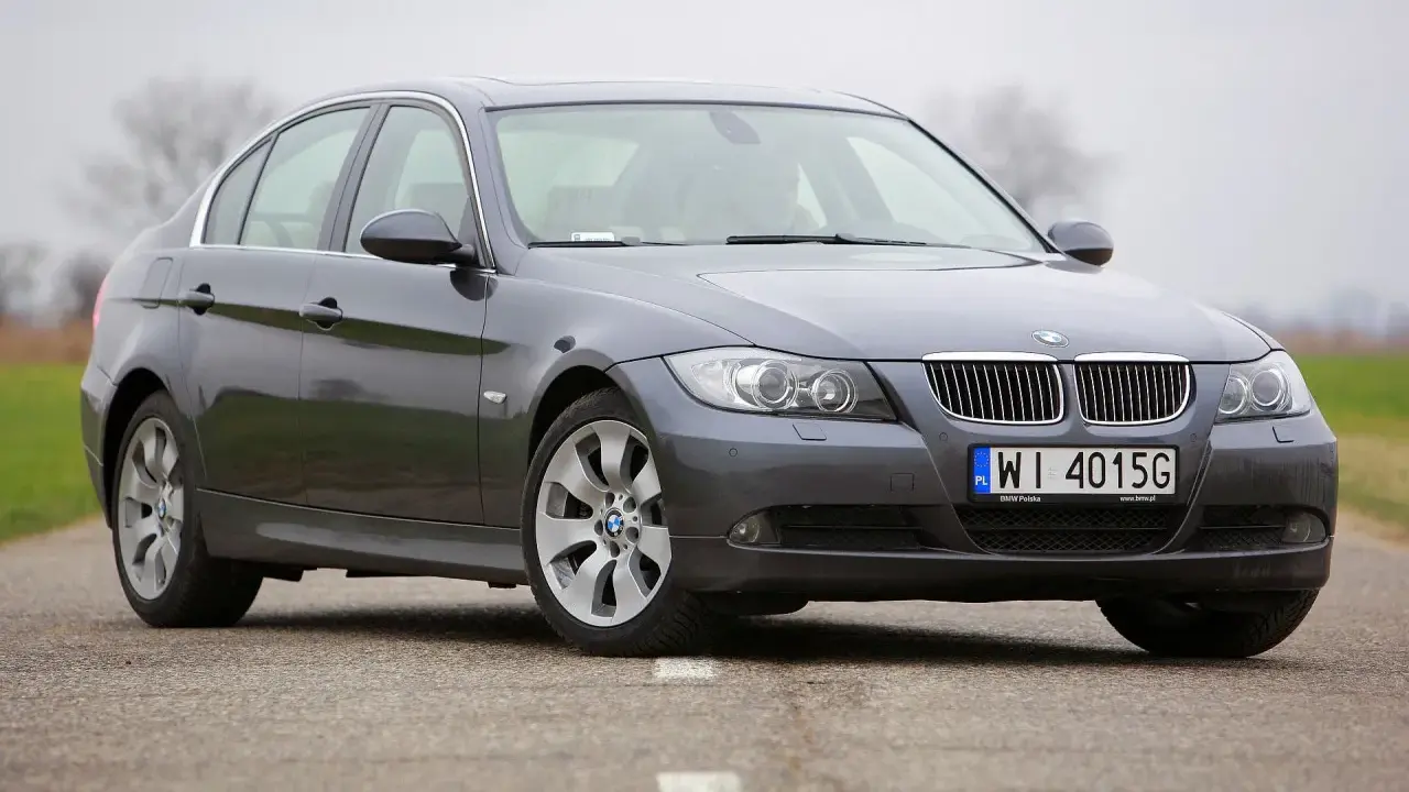 Szary sedan BMW e90 przedlift na drodze. Klasyczna linia nadwozia i charakterystyczne "nerki" na grillu.