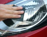 Dłoń z papierem ściernym poleruje reflektor. Po takim zabiegu warto pomyśleć, czym zabezpieczyć lampy po polerowaniu, by efekt był trwały.