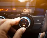 Dłoń reguluje pokrętłem klimatyzację samochodową, ustawiając temperaturę 25.0 stopni.
