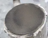 Filtr cząstek stałych (DPF) w samochodzie. Widoczny metalowy wkład z drobnymi otworami, który zatrzymuje sadzę.