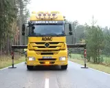 Żółta ciężarówka ADAC z wysięgnikiem przygotowana do holowania na drodze ekspresowej.