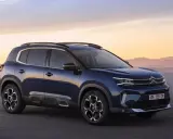 Ciemnoniebieski, kompaktowy SUV Citroën C5 Aircross na tle zachodzącego słońca nad morzem.