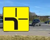 Znak drogi z pierwszeństwem przejazdu i uszkodzony samochód na skrzyżowaniu. Wypadek spowodowany łamanym pierwszeństwem.