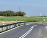 Oznaczenia na słupkach drogowych wzdłuż zakrętu drogi, prowadzącej przez pola i w pobliżu linii energetycznych.