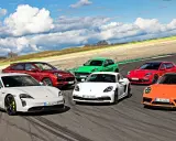 Różne rodzaje Porsche: biały Taycan, czerwony Cayenne, zielony Macan, biały Cayman, czerwona Panamera Sport Turismo i pomarańczowy 911 na torze wyścigowym.