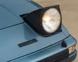 Mazda RX-7 z silnikiem Wankla. Charakterystyczny, wysuwany reflektor i logo marki na niebieskim lakierze.