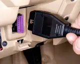 Ręka podłącza kabel do gniazda OBD w samochodzie, aby sprawdzić jego stan.