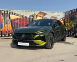 Nowy Peugeot 408 po lifcie, w kolorze zielonym, prezentuje się na tle kolorowych murali na kontenerach.