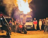 Motocykl z miotaczem ognia, który może wygenerować hałas, o jakim nie śniło się żadnemu autu. Grupa ludzi obserwuje pokaz.