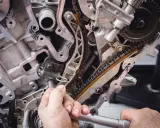 Mechanik naprawia rozrząd silnika. Luźny łańcuch może być jednym z objawów zużytej poduszki silnika.
