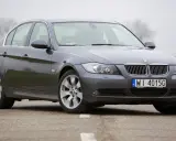 Szary sedan BMW e90 przedlift na drodze. Klasyczna linia nadwozia i charakterystyczne "nerki" na grillu.