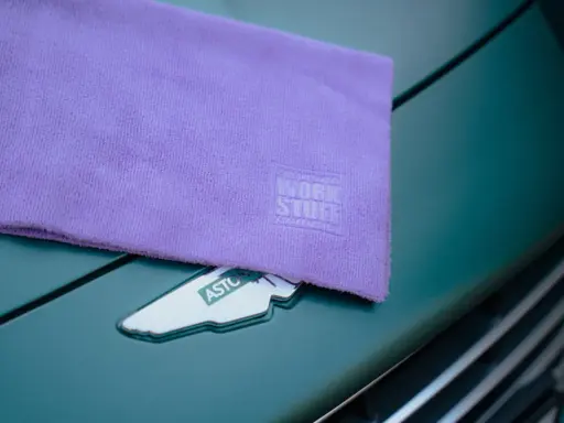 Fioletowa mikrofibra z logo Work Stuff na masce zielonego samochodu. Idealna do pielęgnacji lakieru.