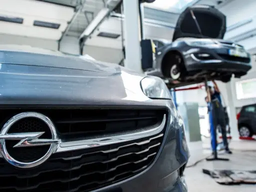 Warsztat samochodowy, gdzie mechanik sprawdza, co wymieniać w samochodzie. Na pierwszym planie grill Opla.