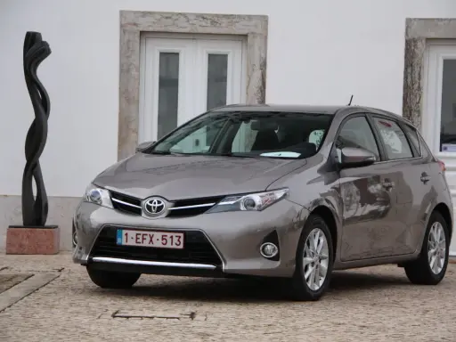 Szary Toyota Auris 1.6 benzyna, idealny do miasta, z niskim spalaniem. Obok rzeźba.