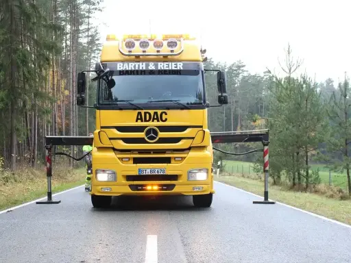 Żółta ciężarówka ADAC z wysięgnikiem przygotowana do holowania na drodze ekspresowej.