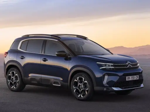 Ciemnoniebieski, kompaktowy SUV Citroën C5 Aircross na tle zachodzącego słońca nad morzem.