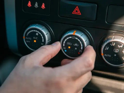Dłoń kręci pokrętłem klimatyzacji, próbując zdiagnozować objawy zepsutego termostatu.