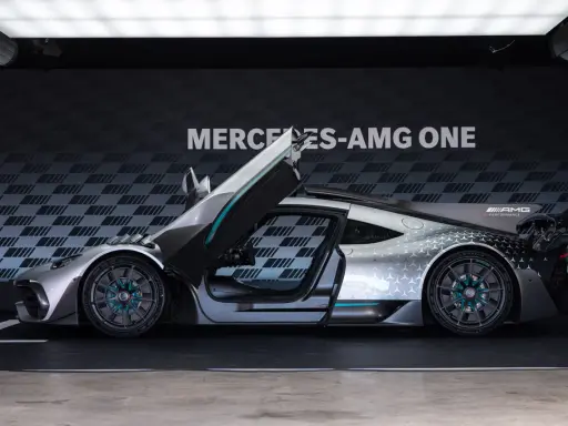 Srebrny Mercedes-AMG ONE z otwartymi drzwiami i maską, prezentujący futurystyczny design i sportowe osiągi.