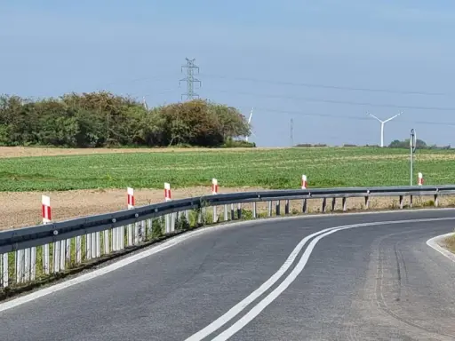 Oznaczenia na słupkach drogowych wzdłuż zakrętu drogi, prowadzącej przez pola i w pobliżu linii energetycznych.