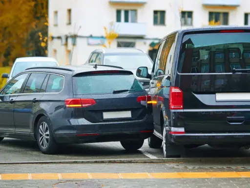 Ciemny kombi zaparkowany zbyt blisko drugiego samochodu, ledwo mieszcząc się na miejscu parkingowym.