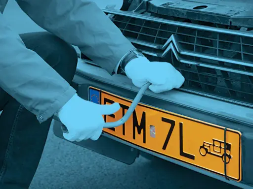 Ręce w białych rękawiczkach montują żółtą tablicę rejestracyjną z symbolem starego auta. Czy warto zarejestrować auto jako zabytek?