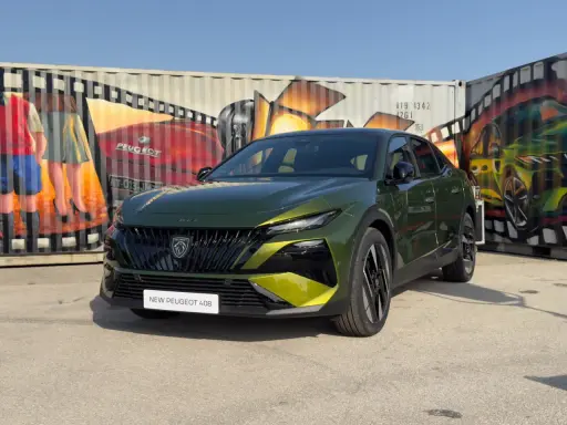 Nowy Peugeot 408 po lifcie, w kolorze zielonym, prezentuje się na tle kolorowych murali na kontenerach.