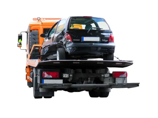 Pomoc drogowa pokazuje, jak holować auto po wypadku. Uszkodzony czarny Renault Twingo jest ładowany na lawetę.