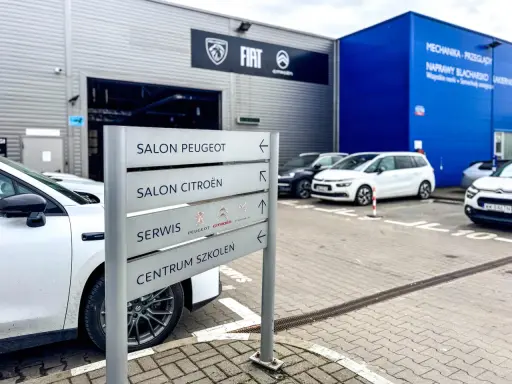 Znak kierunkowskazów w ASO wskazuje salon Peugeot, salon Citroën, serwis i centrum szkoleń.