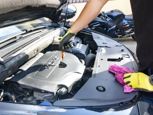 Sprawdzanie poziomu oleju silnikowego przed zmianą z 5w40 na 5w30. W tle widać motocykl.