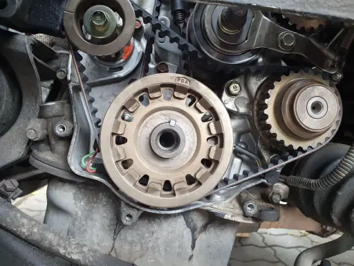 Zbliżenie na mechanizm silnika, widoczne koła zębate i pasek. Przygotowanie do wymiany rozrządu.