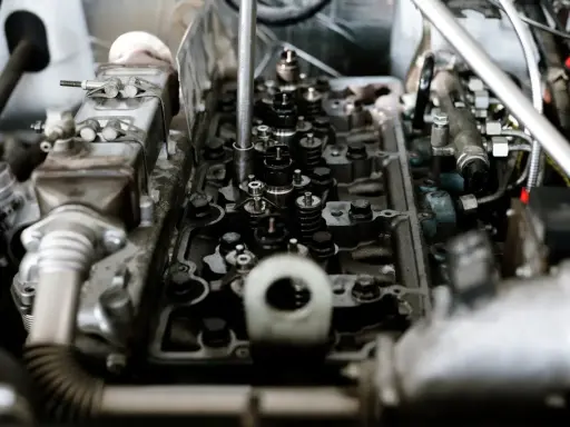 Mechanik bada silnik, szukając przyczyn spalania stukowego. Widoczne zawory i wtryskiwacze.