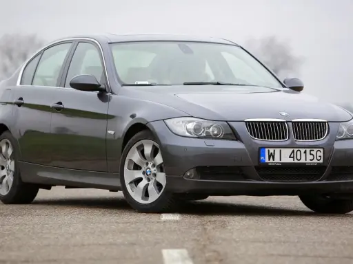 Szary sedan BMW e90 przedlift na drodze. Klasyczna linia nadwozia i charakterystyczne "nerki" na grillu.