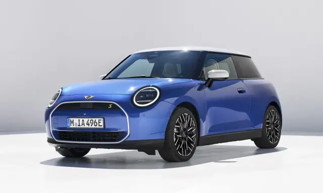 Niebieski Mini Cooper z białym dachem, jeden z tych małych aut, które pokochasz.