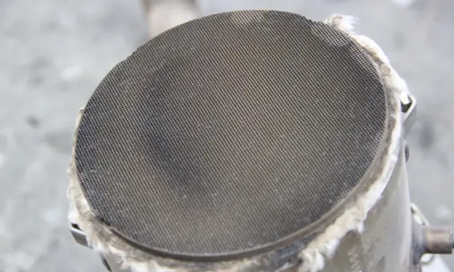 Filtr cząstek stałych (DPF) w samochodzie. Widoczny metalowy wkład z drobnymi otworami, który zatrzymuje sadzę.