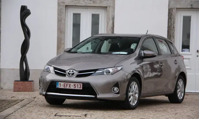 Szary Toyota Auris 1.6 benzyna, idealny do miasta, z niskim spalaniem. Obok rzeźba.
