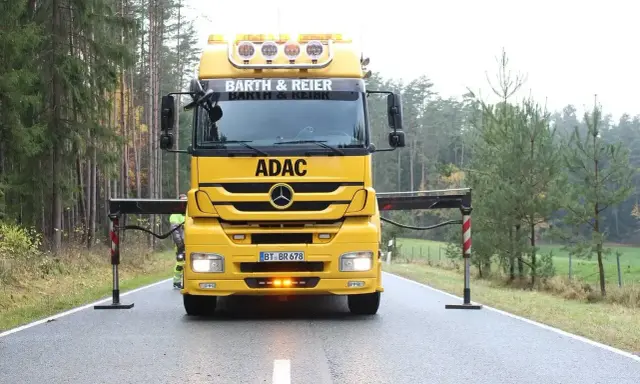 Żółta ciężarówka ADAC z wysięgnikiem przygotowana do holowania na drodze ekspresowej.